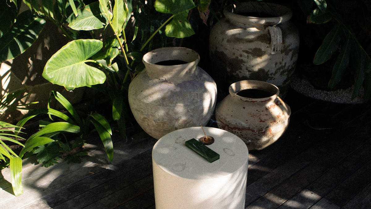 Decorative pots on a wooden deck with greenery in the background