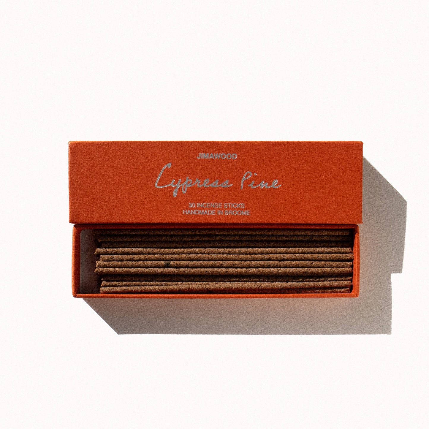 
                  
                    An orange cardboard box slightly opened on a plain background. Text on the box: Jimawood Cypress Pine 30 Incense Sticks Handmade in Broome
                  
                