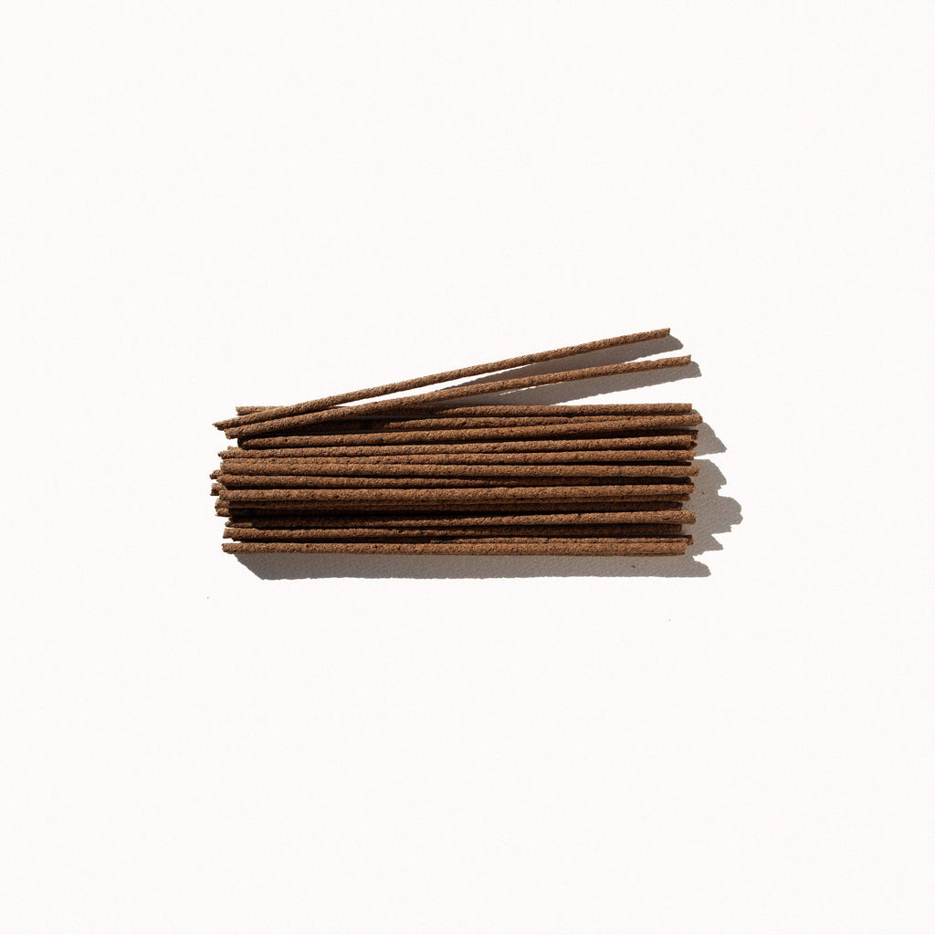 A small pile of brown incense sticks on a plain background.