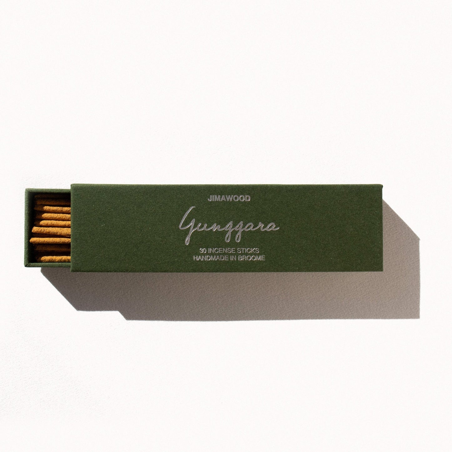 A green cardboard box slightly opened on a plain background. Text on the box: Jimawood Gunggara 30 Incense Sticks Handmade in Broome