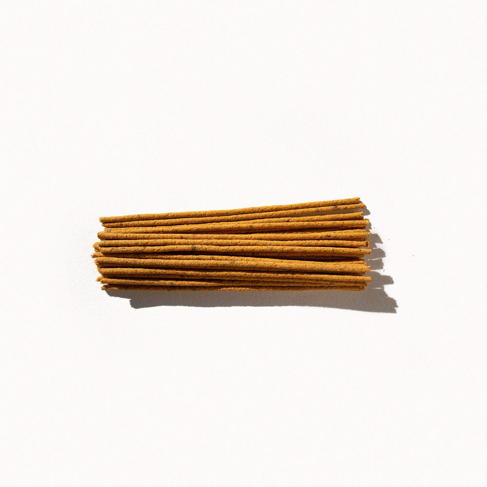 
                  
                    A small pile of yellow incense sticks on a plain background. 
                  
                