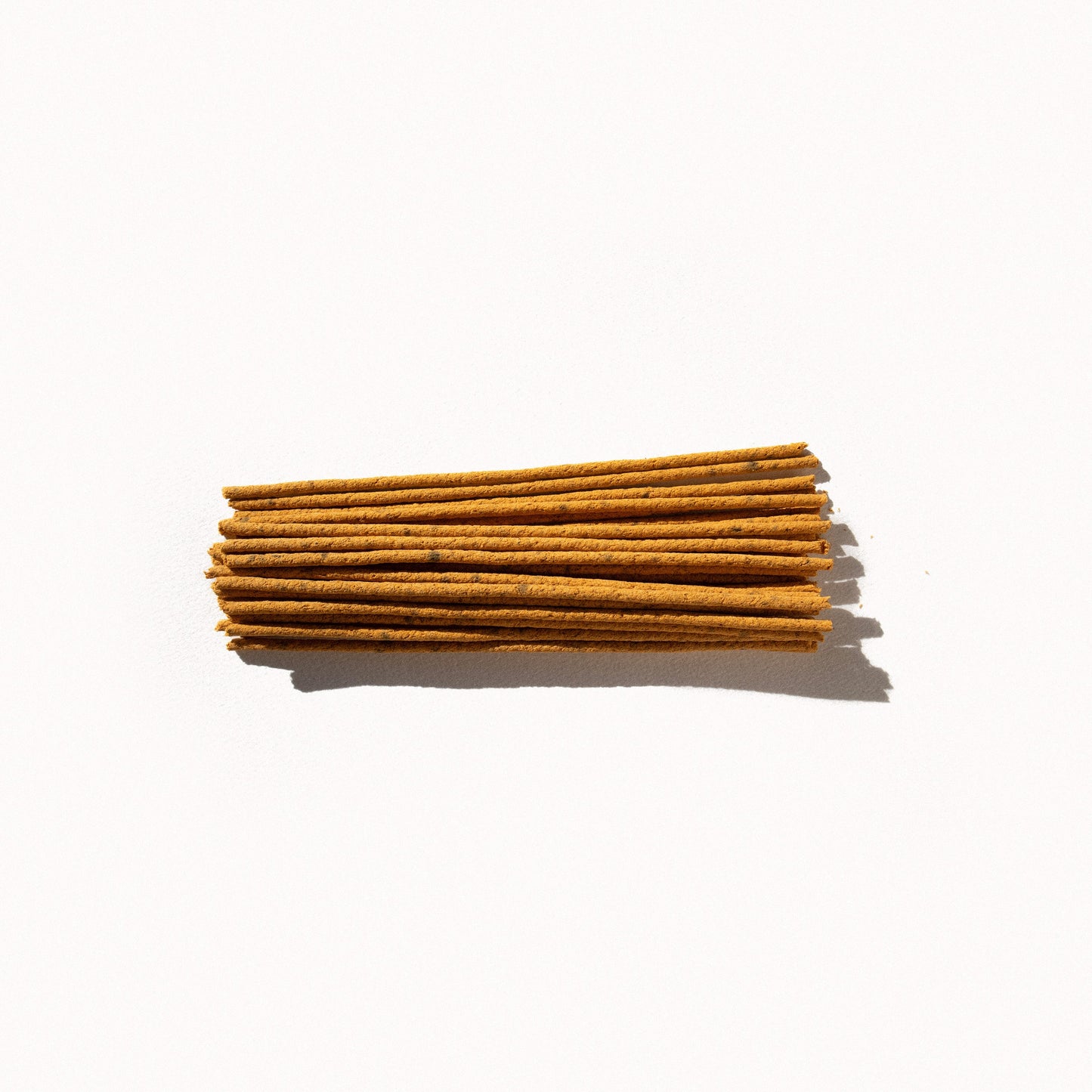 
                  
                    A small pile of yellow incense sticks on a plain background. 
                  
                